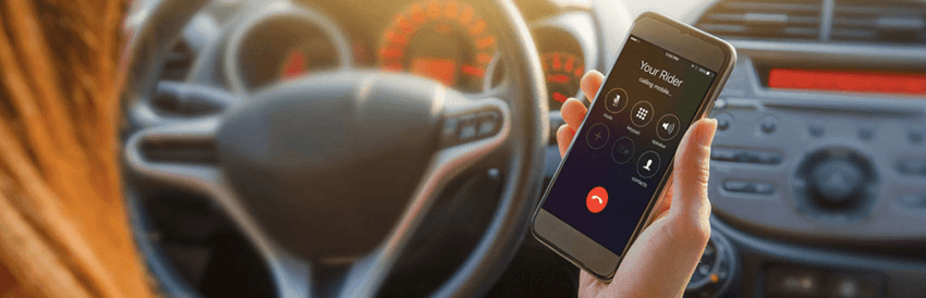 Pessoa dentro do carro segurando o telefone com o aplicativo Grab aberto